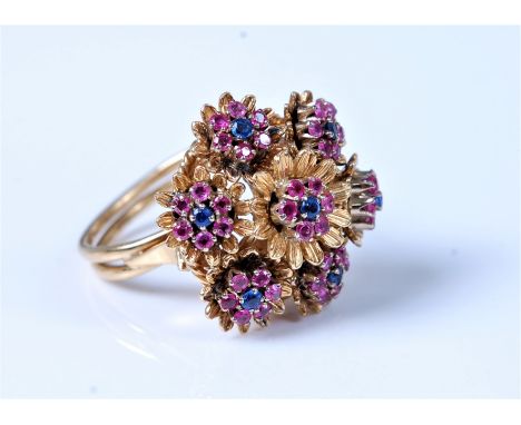 An 18ct sapphire and ruby cocktail ring, the central sapphire and ruby stamens in a surround of gold petals, surrounded by si