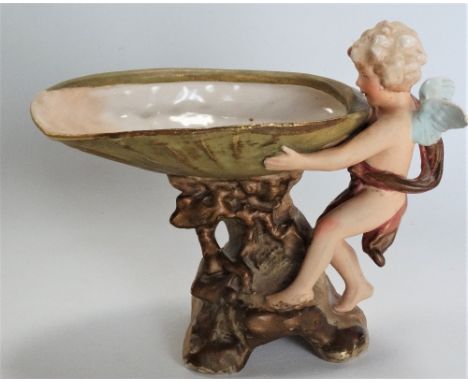 A 19th century Royal Dux Pottery table centrepiece modelled as a cherub holding a shell upon a naturalistic base, No.1745, pi