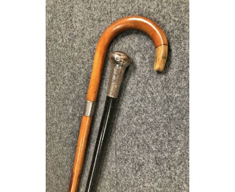 An Edwardian silver topped ebonised walking cane, together with a walking stick with silver band decoration.