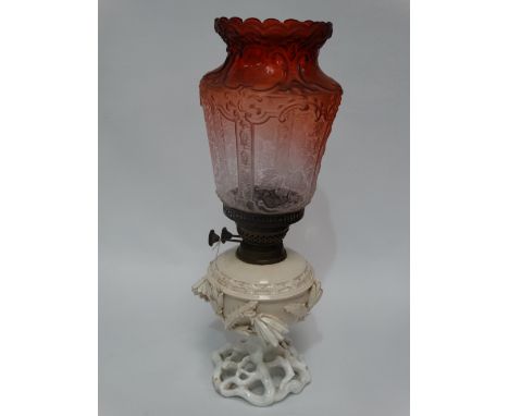 A pottery oil lamp base foliate encrusted with a orange blush glass etched shade, height 48cm. 