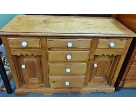 A Victorian stripped pine side cabinet fitted six drawers and two cupboards with white ceramic knob handles, width 118cm. 