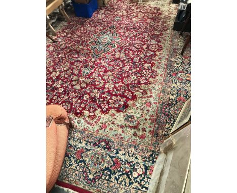 A Kerman hand knotted carpet, with foliate scroll decoration on a burgundy ground and within borders, 295 x 398cm. 