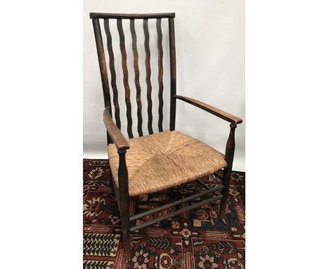 An Arts &amp; Crafts armchair with rush seat and wavy stick back. 