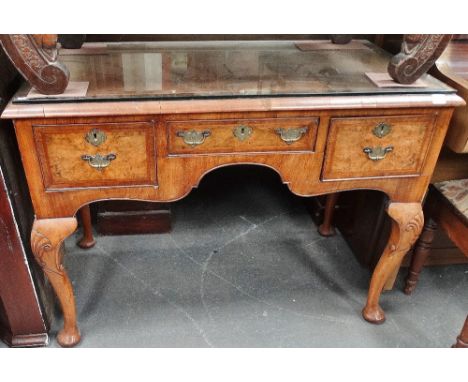 A walnut and crossbanded Queen Anne style dressing table fitted three drawers above shell capped cabriole legs, width 105cm. 