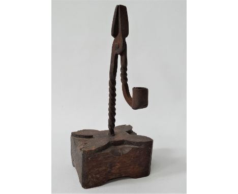 A Georgian iron rush light holder, upon original oak rectangular base carved with a quadraform design, height 24cm.