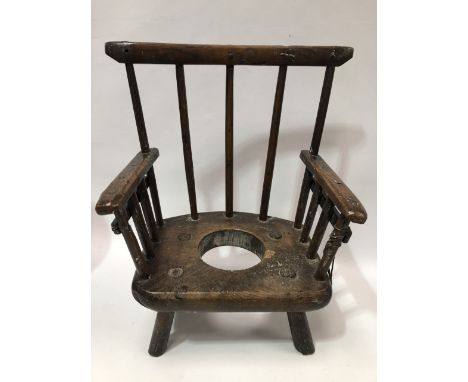 An early English or Welsh child's elm commode chair with stickback slab seat and turned legs, with good patination.