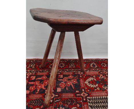 An early 18th century elm tripod table, the top of canted rectangular shape raised on three tapering legs with traces of orig