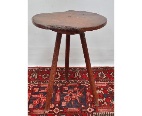 An early 18th century elm tripod table, the top of broken circular shape raised on three tapering legs with traces of origina