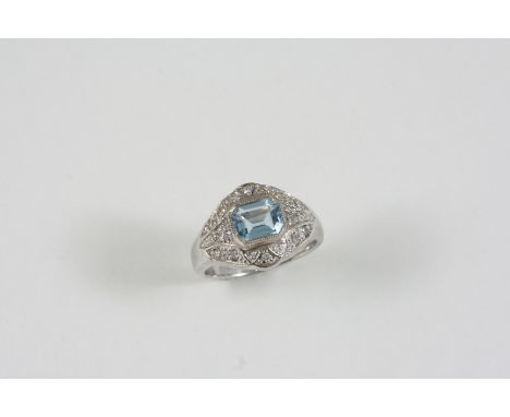 AN AQUAMARINE AND DIAMOND CLUSTER RING the step-cut aquamarine is set within a surround of small diamonds, in white gold. Siz