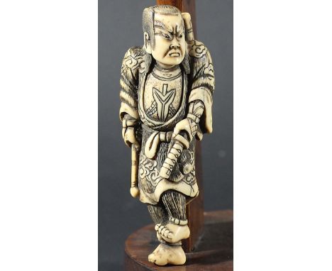 JAPANESE IVORY NETSUKE, carved as a samurai holding his sword, 10cm