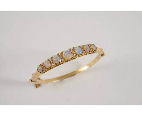 AN EARLY 20TH CENTURY OPAL AND DIAMOND HALF HINGED BANGLE set to one side with graduated oval cabochon solid white opals and 