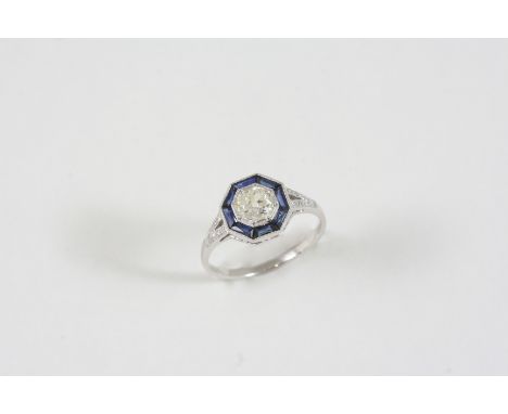 A SAPPHIRE AND DIAMOND CLUSTER RING the circular-cut diamond is set within a surround of calibre-cut sapphires, with circular