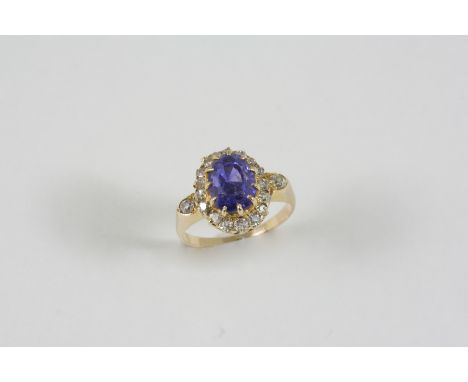 A TANZANITE AND DIAMOND CLUSTER RING the oval-shaped tanzanite is set within a surround of circular-cut diamonds, in 18ct. go
