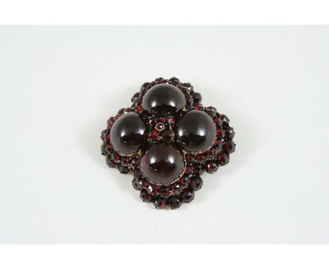 A VICTORIAN GARNET BROOCH the quatrefoil design is mounted with four circular cabochon garnets within a surround of circular 