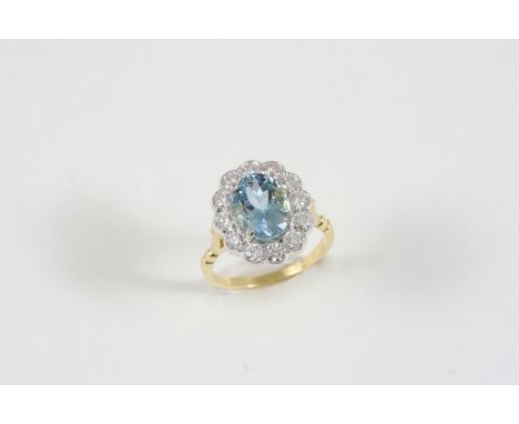 AN AQUAMARINE AND DIAMOND CLUSTER RING the oval-shaped aquamarine is set within a surround of twelve circular -cut diamonds i