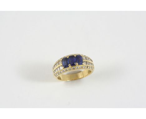 A SAPPHIRE AND DIAMOND RING the 18ct. gold band is centred with three octagonal-shaped sapphires, with baguette-cut diamonds 