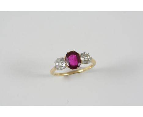 A RUBY AND DIAMOND THREE STONE RING the oval-shaped ruby is set with two old brilliant-cut diamonds, in gold. Size R 1/2.