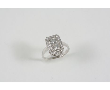 A DIAMOND CLUSTER RING the two central circular-cut diamonds are set within a surround of smaller circular-cut diamonds, in 1