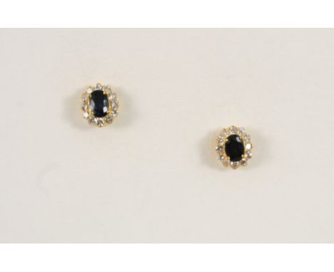 A PAIR OF SAPPHIRE AND DIAMOND CLUSTER STUD EARRINGS each set with an oval-shaped sapphire within a surround of circular-cut 