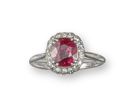 A ruby and diamond cluster ring, the cushion-shaped ruby set within a surround of single-cut diamonds in platinum, size M