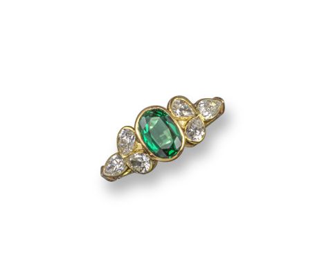 An emerald and diamond cluster ring, the oval-shaped emerald is rubover-set in yellow gold with a trefoil of pear-shaped diam