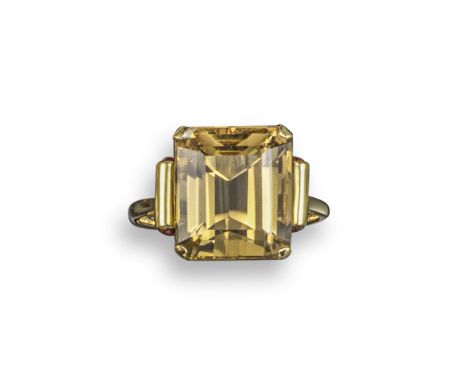 A citrine and ruby-set gold ring, c. 1940, the emerald-cut citrine is claw-set with ruby cabochons to the shoulders in yellow