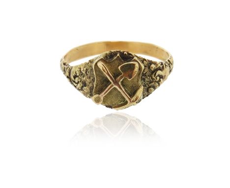 An Australian gold mining ring, centred with a cartouche applied with a cross, pick-axe and shovel on matted ground, the shou