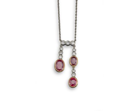 A ruby and diamond lavalier, the diamond-set upper section suspends two asymmetrical drops set with oval-shaped rubies and ro