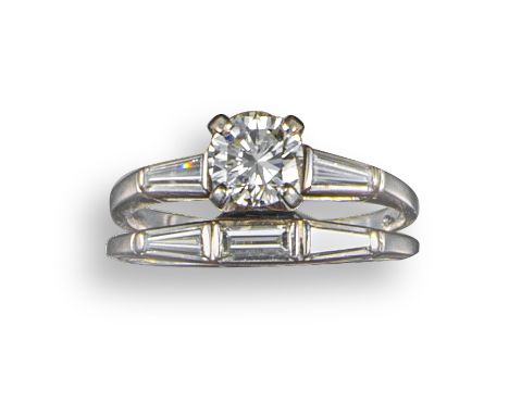 A diamond three-stone ring, set with a round brilliant-cut diamond weighing approximately 0.65cts with tapered baguette-shape