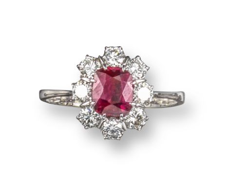 A ruby and diamond cluster ring, the cushion-shaped ruby is set within a surround of round brilliant-cut diamonds in white go