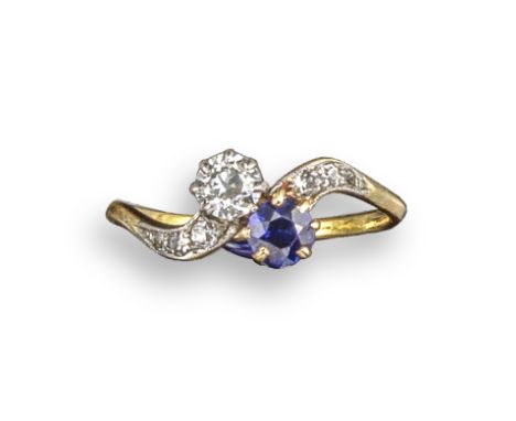 A sapphire and diamond crossover ring, set with a round brilliant-cut sapphire and diamond, with diamond-set shoulders in pla