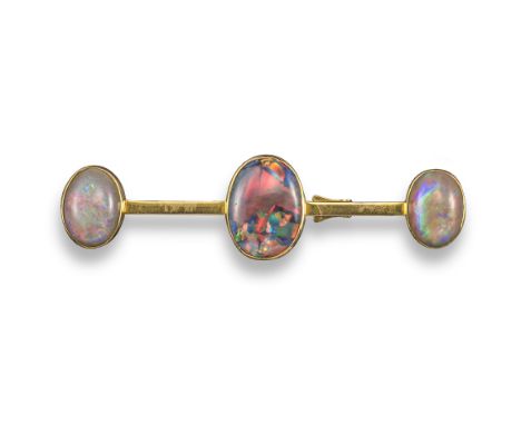 A gold brooch set with three oval-shaped opals, the centre oval-shaped solid black opal displays a selection of colours and i