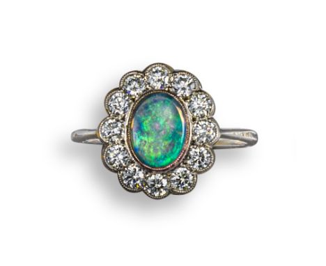 An opal and diamond cluster ring, the opal set within a surround of round brilliant-cut diamonds in platinum, size Q