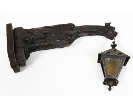 A 19th Century grotesque carved oak wall light fitting formed as a mythical griffin with metal and yellow glass hanging lante