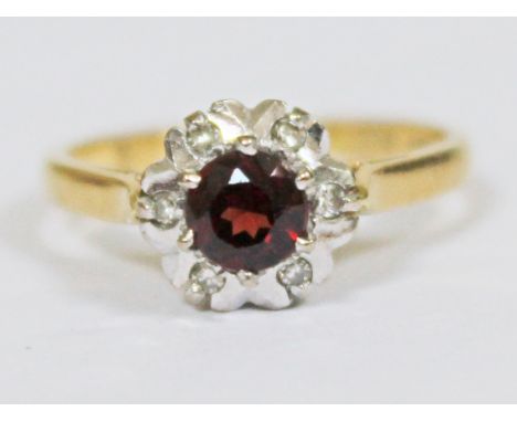 A flower head ring set with a garnet surround by six small diamonds, marked '18ct', gross wt. 3.5g, size M.
