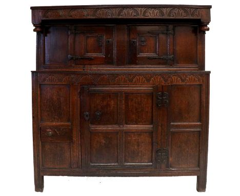 A Late 17th Century Joined Oak Hall Cupboard, the moulded top above a lunette carved frieze above inverted turned finials, th