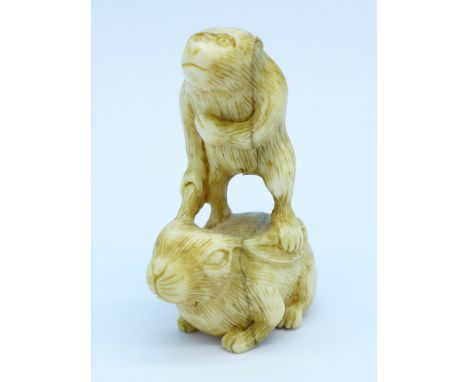 A carved ivory netsuke of an ape riding a rabbit