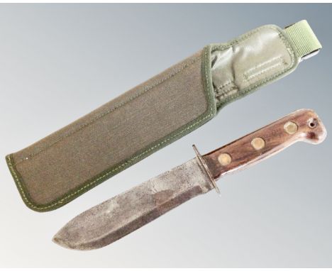 A British Army survival knife with arrow and B2 markings, in canvas scabbard.