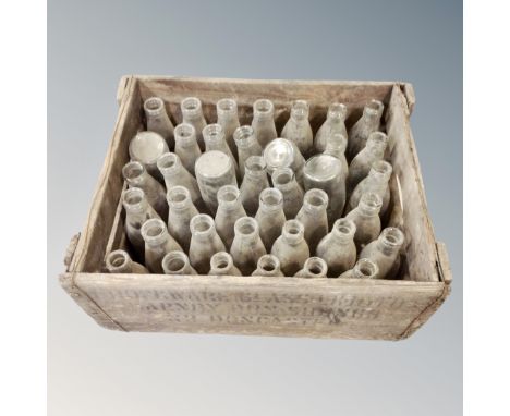 A vintage pine crate containing glass milk bottles 