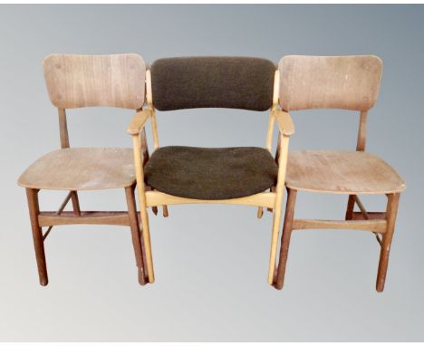 A 20th century light-oak armchair together with two plywood dining room chairs.
