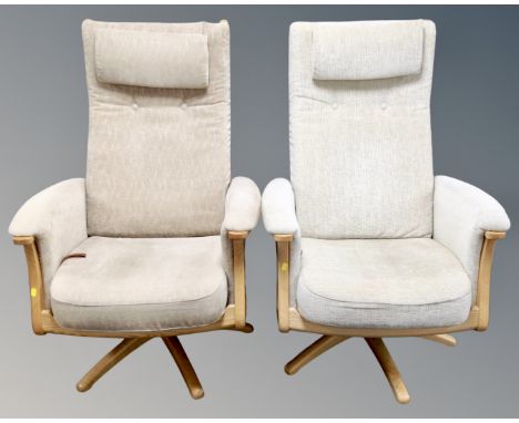A pair of Ercol Gina manual reclining armchairs upholstered in beige fabric with headrests and matching footstools (retailed 