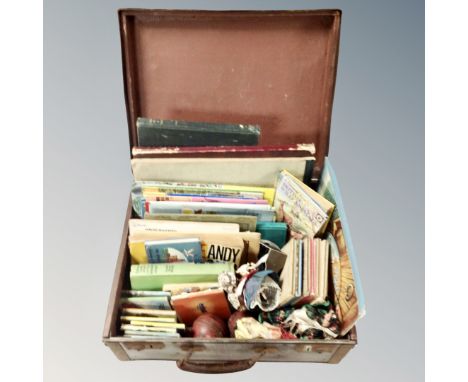 A vintage luggage case containing children's books including Andy Capp, Ladybird, pocket volumes, two cricket balls, dolls, t