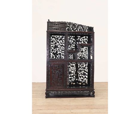 A carved and pierced hardwood cabinet, late Qing dynasty (1644-1911), Chinese, of multistage form, decorated with flying drag