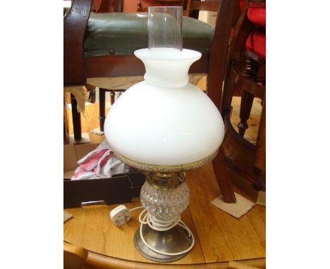 An early 20th Century gilt brass and glass oil lamp with white glass shade, fitted for electricity.