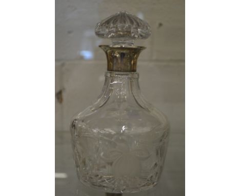 A cut glass decanter with silver collar.