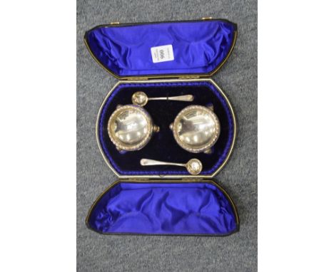A cased pair of circular silver salts with spoons.