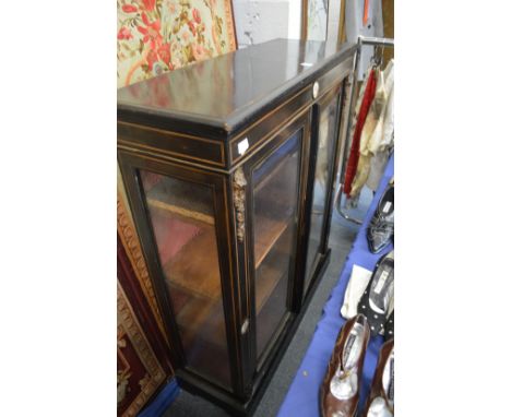 A Victorian ebonised two door display cabinet with ormolu and porcelain mounts.