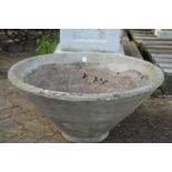 A large circular reconstituted stone garden planter.