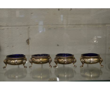 A set of four silver circular salts with blue glass liners.