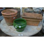 A green glazed planter and two terracotta plant pots.